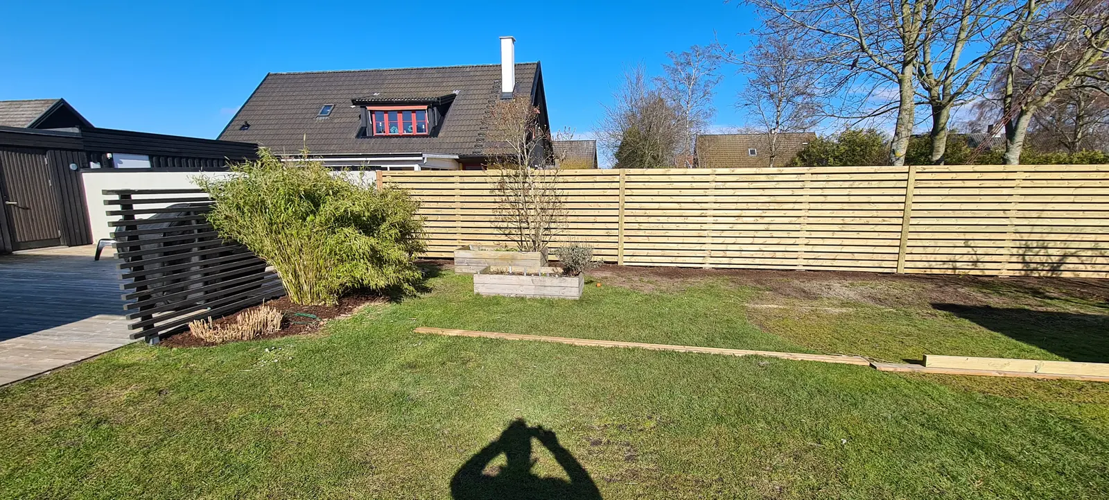 Långt träplank med smala liggande brädor längs en trädgård i Jonstorp